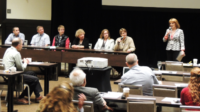 A group of 6 panelists and one moderator speak to a classroom of adults.